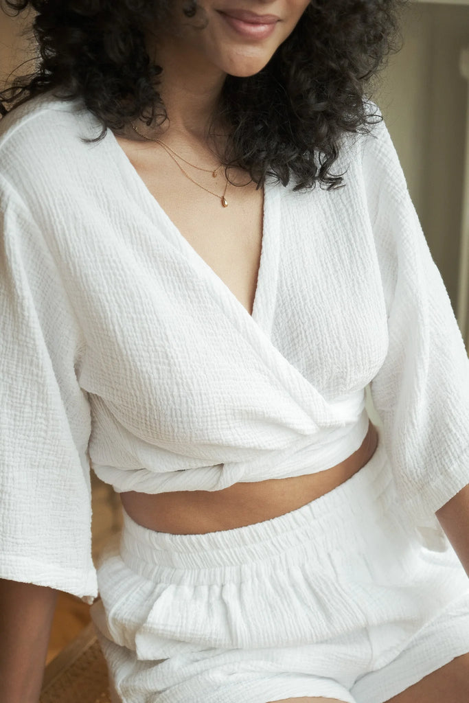 Stylish woman posing in a Bali Wrap Top with a V-neckline, front tie closure, and wide sleeves, highlighting its Turkish cotton fabric.