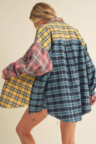 Woman wearing an oversized plaid colorblock flannel shirt in pink, yellow, and navy tones with raw hems.