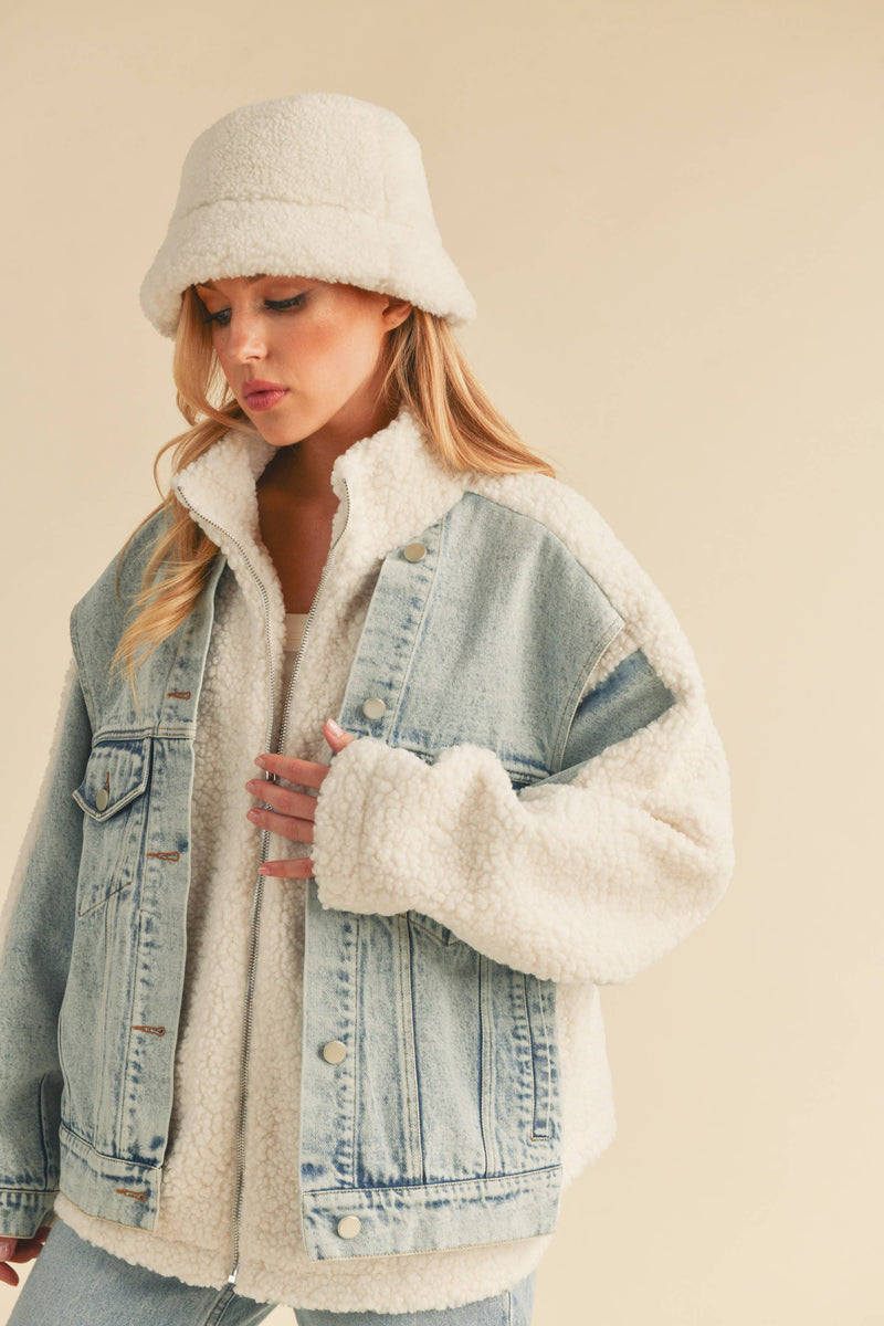 Woman wearing a sherpa-lined denim jacket with a fleece bucket hat, front view.