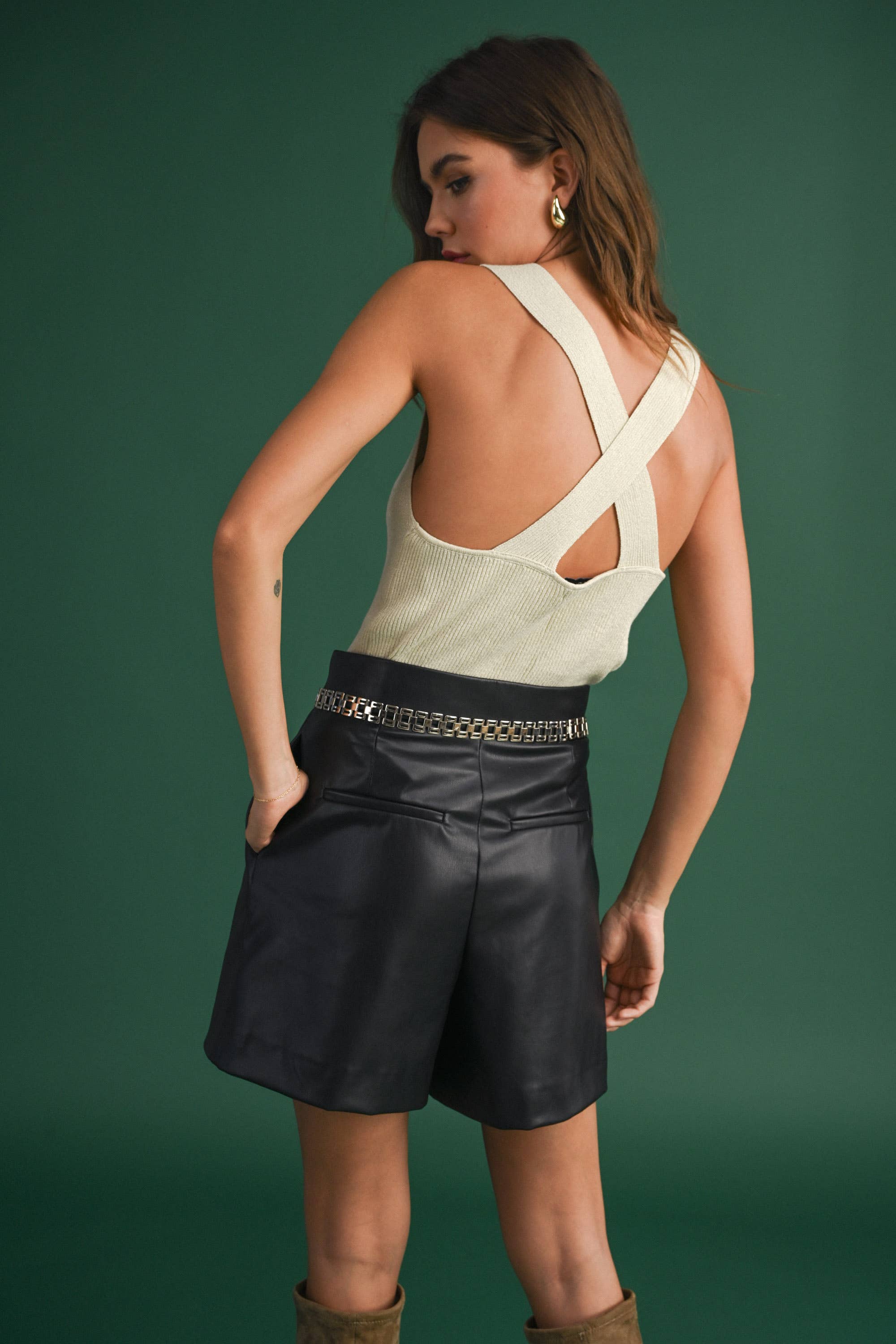 Model wearing a sleeveless ribbed knit top with deep V-neck and cross-back strap detail.