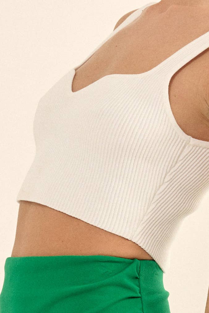 Woman wearing a white ribbed knit crop top with a sweetheart neckline and wide straps.