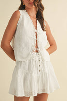 White embroidered cotton set with sleeveless tie-front top and tiered mini skirt featuring scalloped lace trim