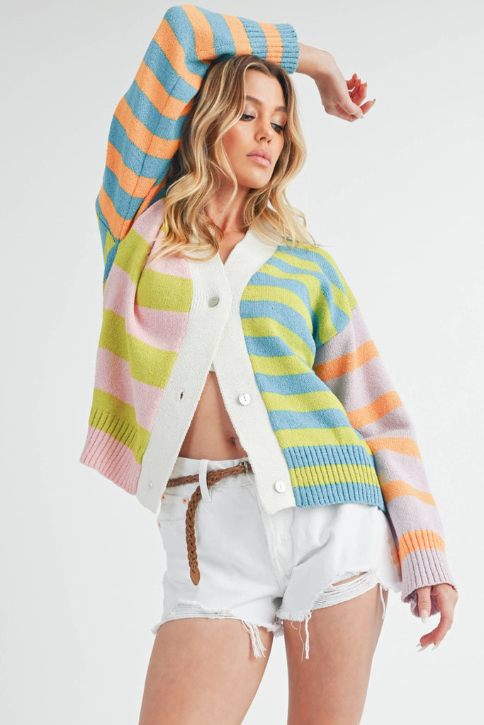Woman wearing a colorful striped cardigan in pink, blue, green, orange, and lilac with a button-front closure.