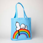 Blue tote bag featuring Snoopy lying on a colorful rainbow, ideal for fans of Peanuts and cheerful accessories.