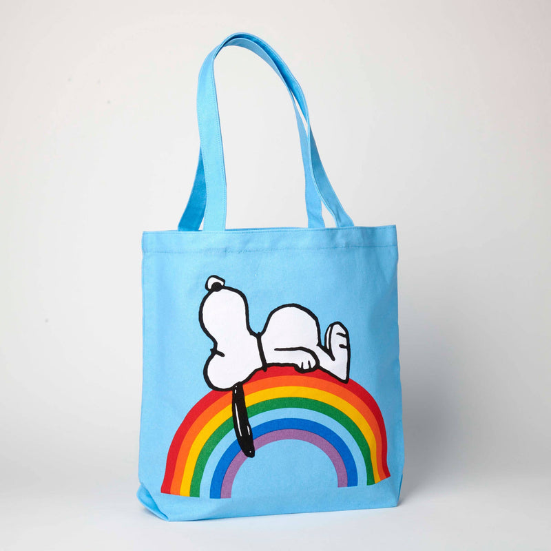 Blue tote bag featuring Snoopy lying on a colorful rainbow, ideal for fans of Peanuts and cheerful accessories.