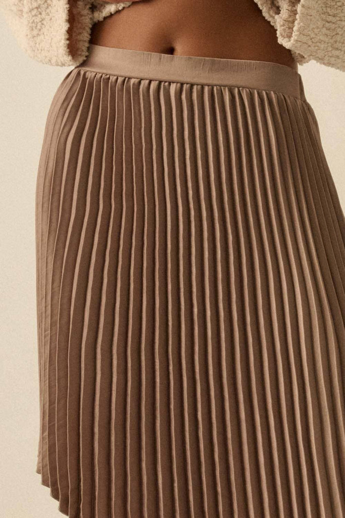Brown asymmetric pleated skirt with flowing high-low hem.