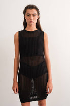 Woman wearing a sleeveless black crochet mini dress.