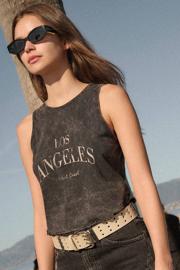 Washed black sleeveless tank top with "Los Angeles West Coast" text, styled with distressed black denim shorts.