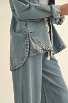 Model in an oversized denim jacket with front pockets. First image: jacket buttoned, paired with white shorts. Second image: jacket open, over a grey tank and denim pants.