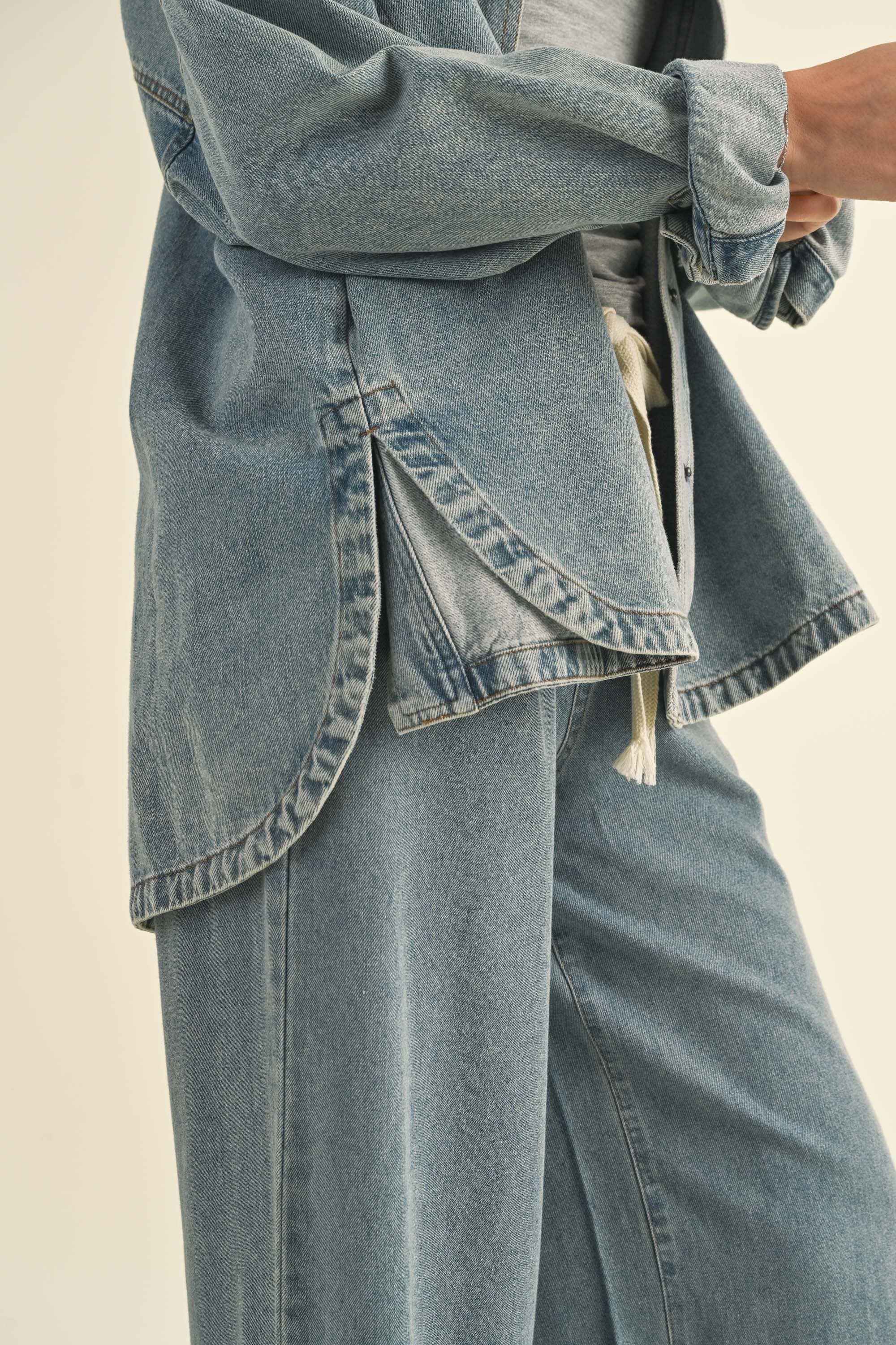 Model in an oversized denim jacket with front pockets. First image: jacket buttoned, paired with white shorts. Second image: jacket open, over a grey tank and denim pants.