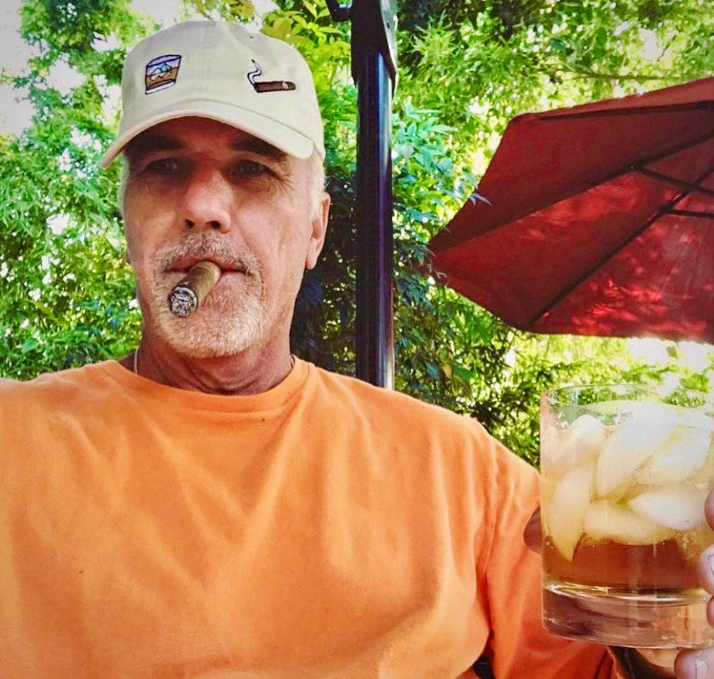 Beige baseball cap with embroidered whiskey glass and cigar design on the front.