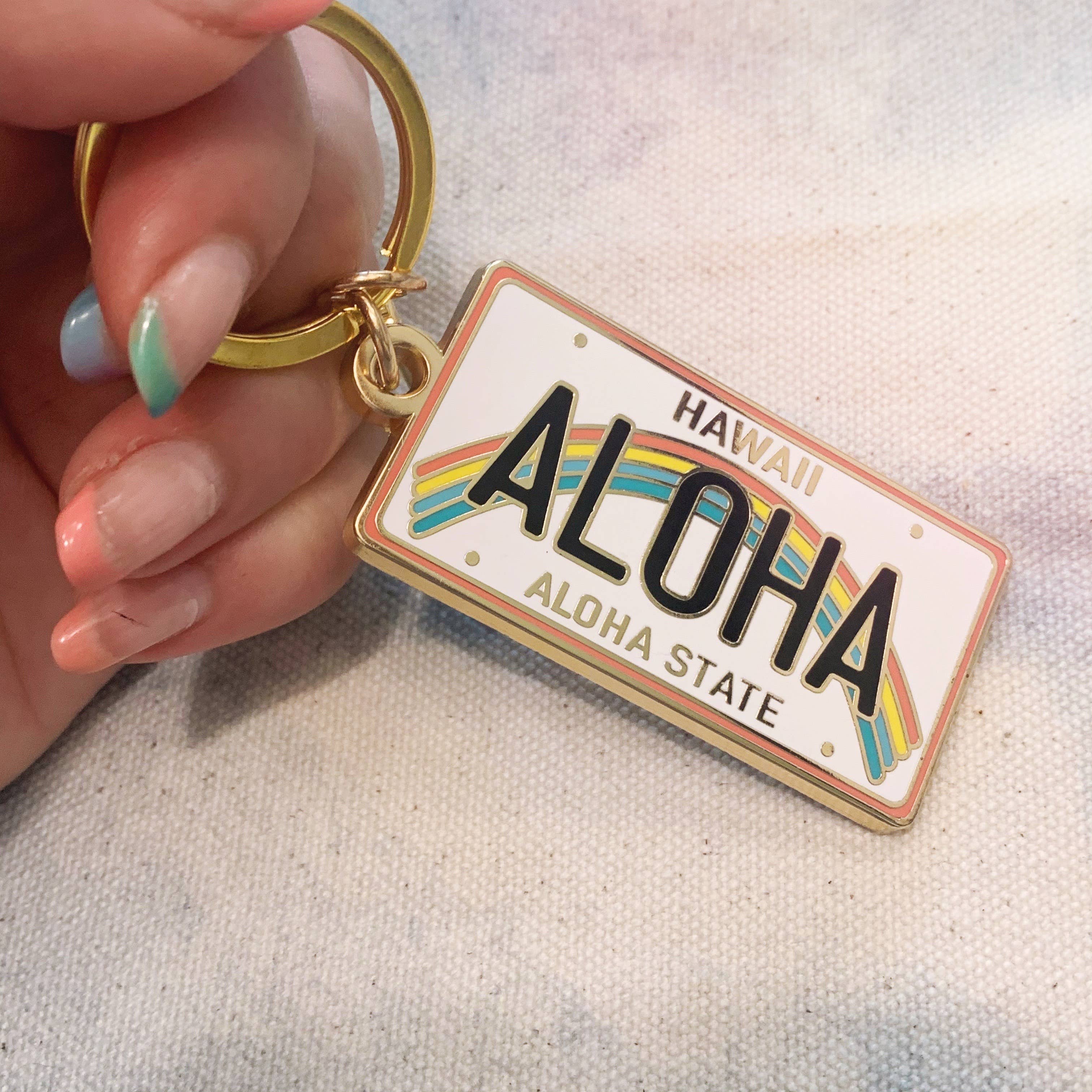Aloha Enamel Keychain featuring a colorful rainbow and “Aloha” text.