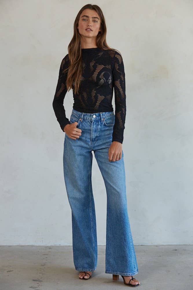 Model wearing the Celestine Lace Top in cream and black lace with long sleeves and floral mesh pattern