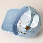 Light blue denim cap with embroidered design on a beige background