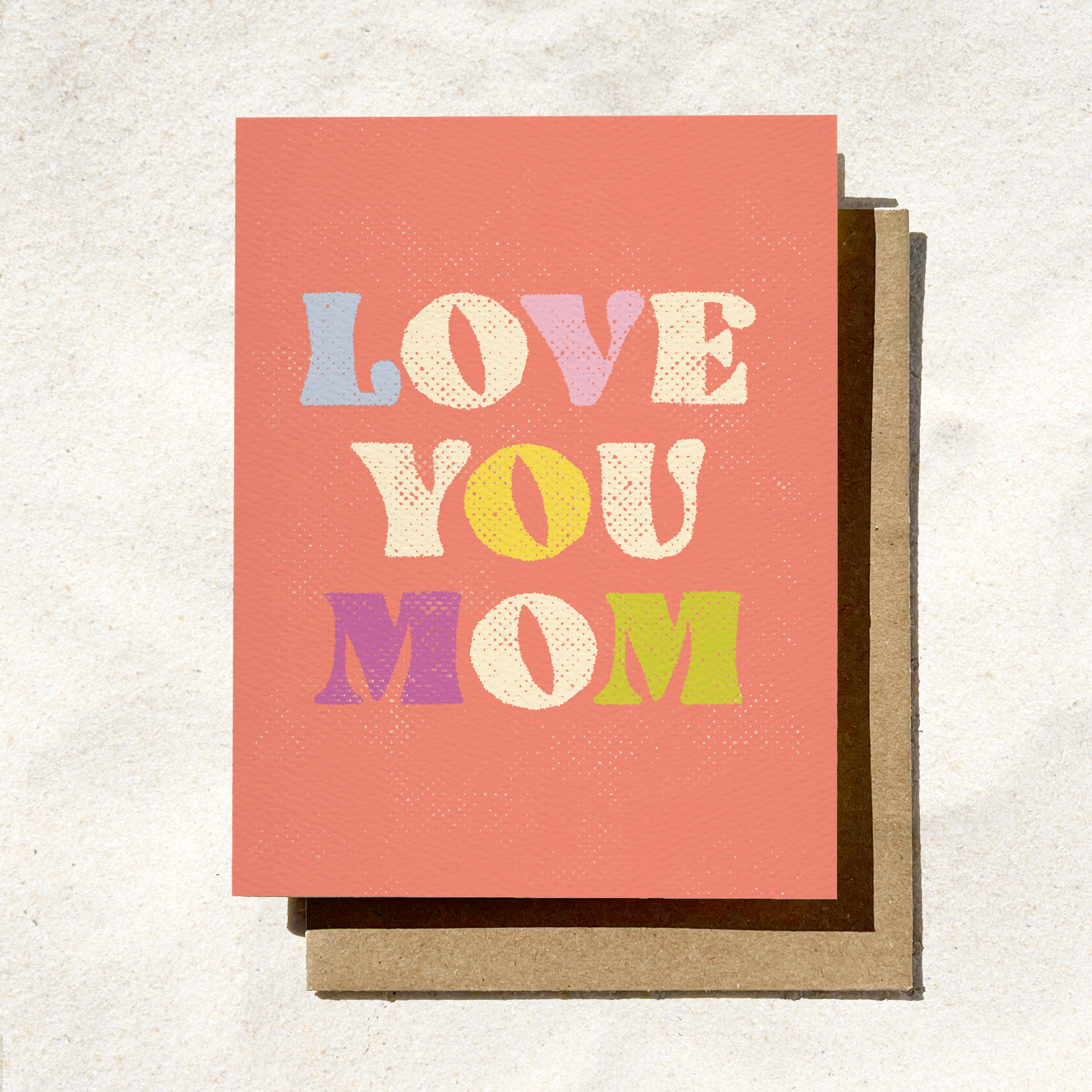 Greeting card with "Love You Mom" written in colorful, retro-style text on a coral background.