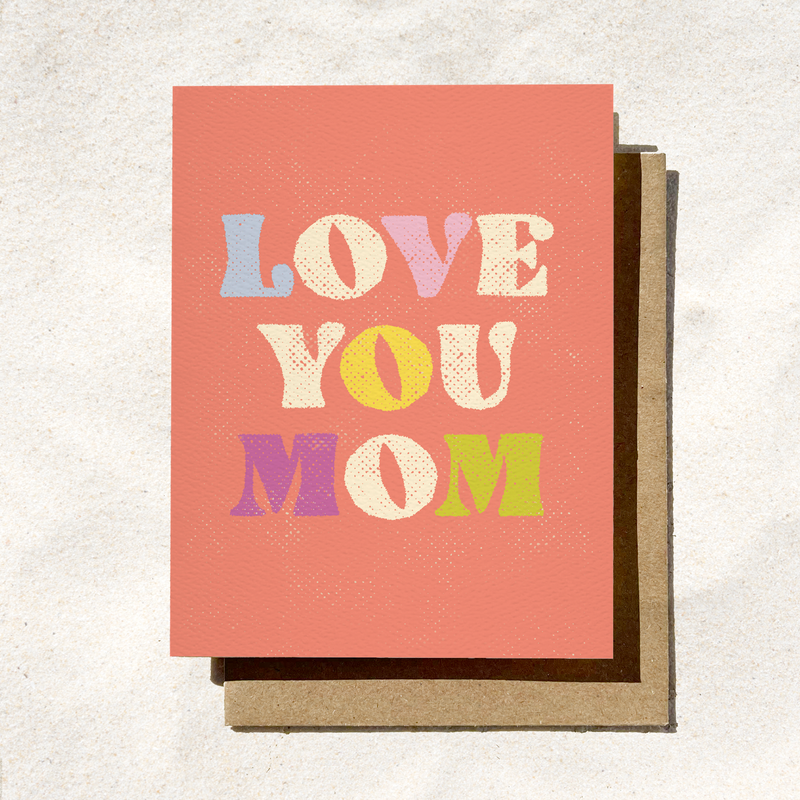 Greeting card with "Love You Mom" written in colorful, retro-style text on a coral background.