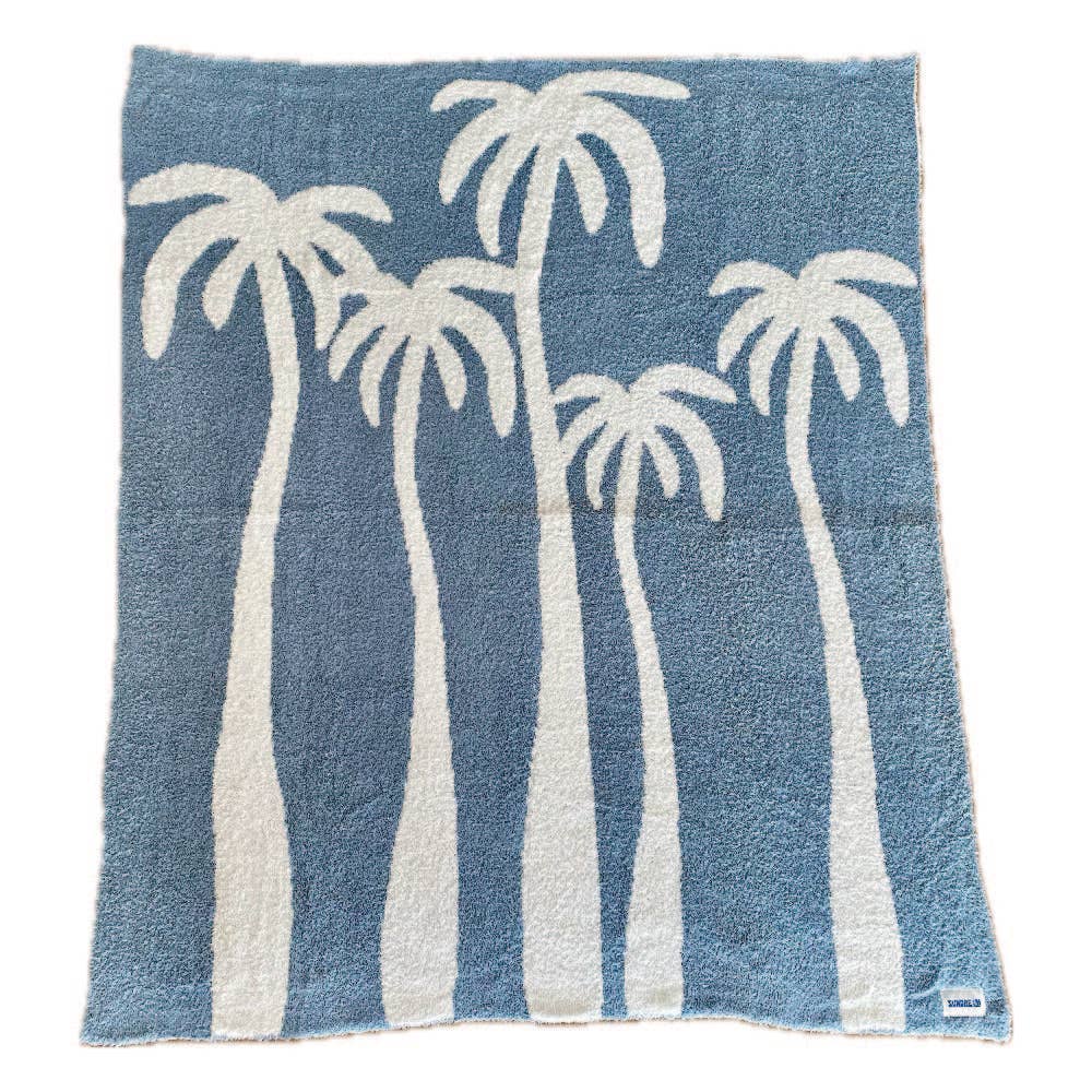 Soft chambray blue plush throw with palm tree design, perfect for cozying up or adding a beachy touch to any space.
