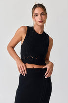 Woman wearing a black sleeveless crochet top and midi skirt set.