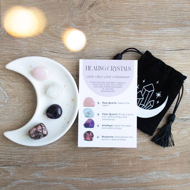 Love Crystal Set featuring a crescent moon trinket dish, rose quartz, clear quartz, amethyst, and rhodonite stones, displayed with a matching information card and a printed drawstring pouch.