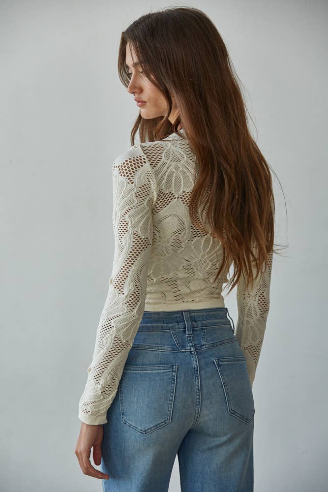 Model wearing the Celestine Lace Top in cream and black lace with long sleeves and floral mesh pattern