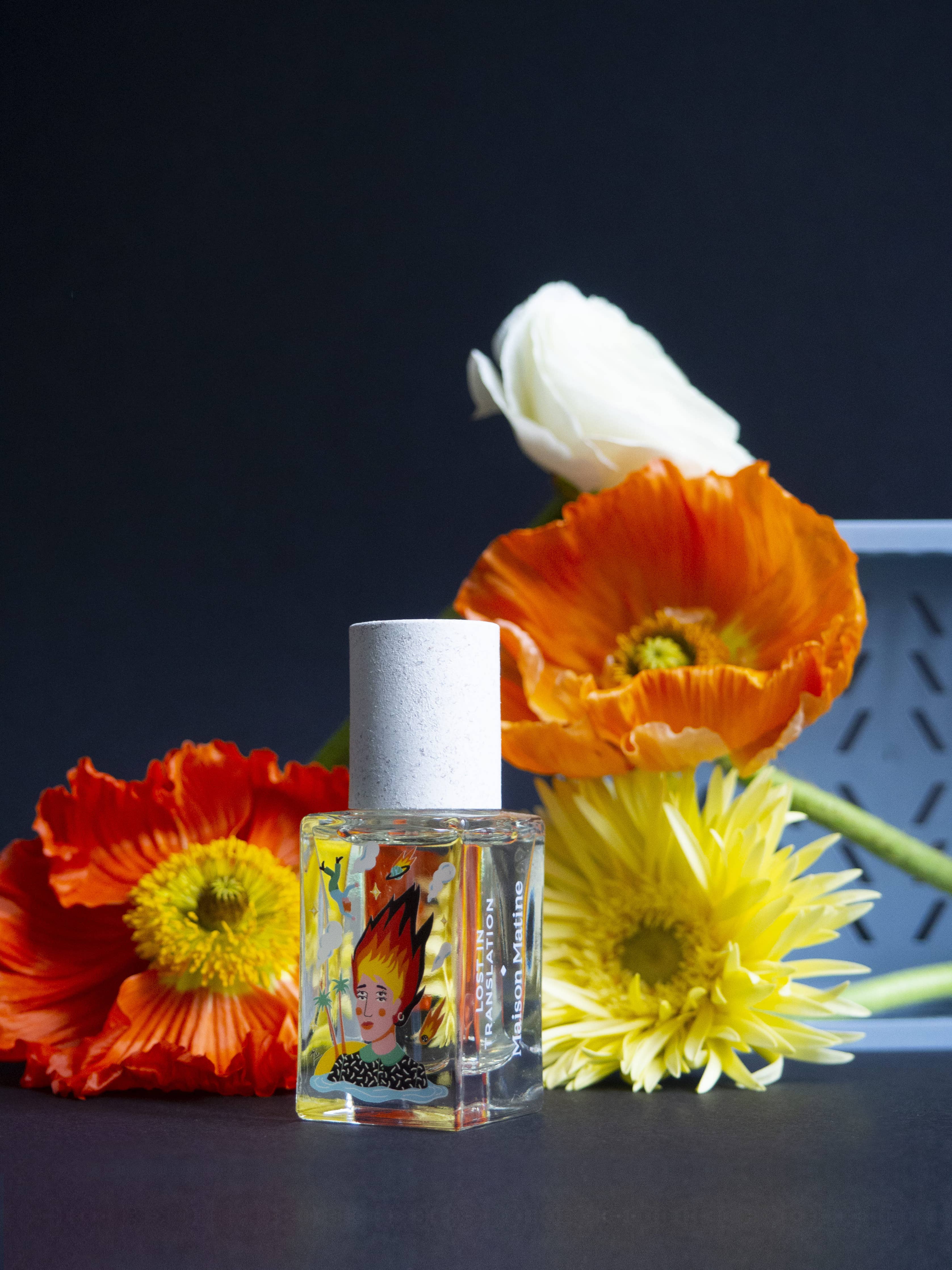 Maison Matine Lost in Translation perfume bottle with bold illustrated design, placed on vibrant yellow textured surface.