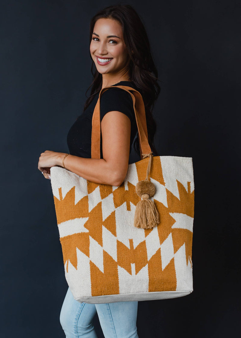Large mustard and ivory woven tote bag with geometric pattern, leather handles, and a tassel accent
