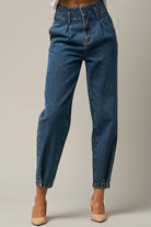  Model wearing high-waist balloon jeans with a relaxed silhouette and slightly tapered legs, paired with a casual graphic t-shirt and neutral heels.