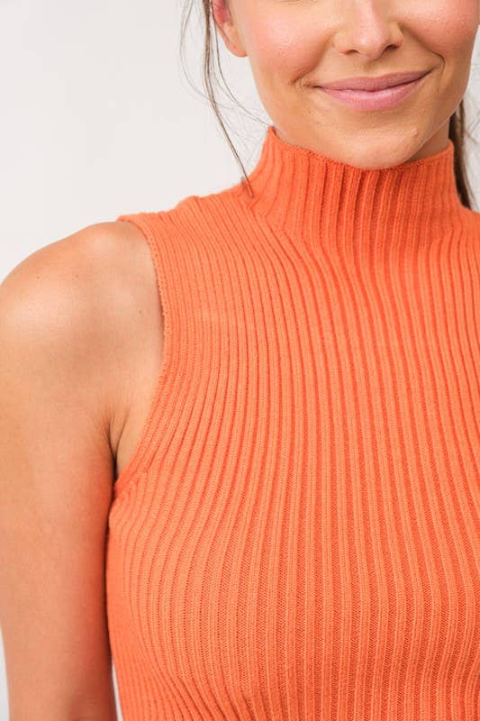 Woman wearing a cropped orange mock neck ribbed knit sweater.