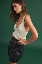 Model wearing a sleeveless ribbed knit top with deep V-neck and cross-back strap detail.