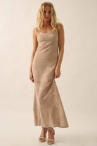 Woman wearing a sheer white lace maxi dress with spaghetti straps and floral detailing.