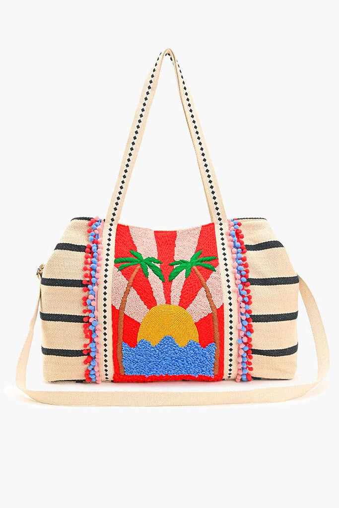 Beaded tote bag with sunset, palm tree, and ocean design, featuring black stripes, colorful pom-pom trim, and long handles.