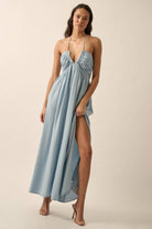 Woman wearing a light blue halter maxi dress with a plunging neckline, side slit, and flowy fit.