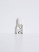 Maison Matine Avant l’Orage perfume bottle with celestial illustrations, placed among citrus fruits and sample vials on blue fabric