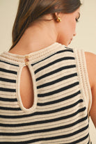 Woman wearing a sleeveless knit romper with black and cream stripes and a drawstring waist.