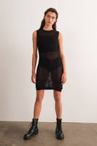 Woman wearing a sleeveless black crochet mini dress.