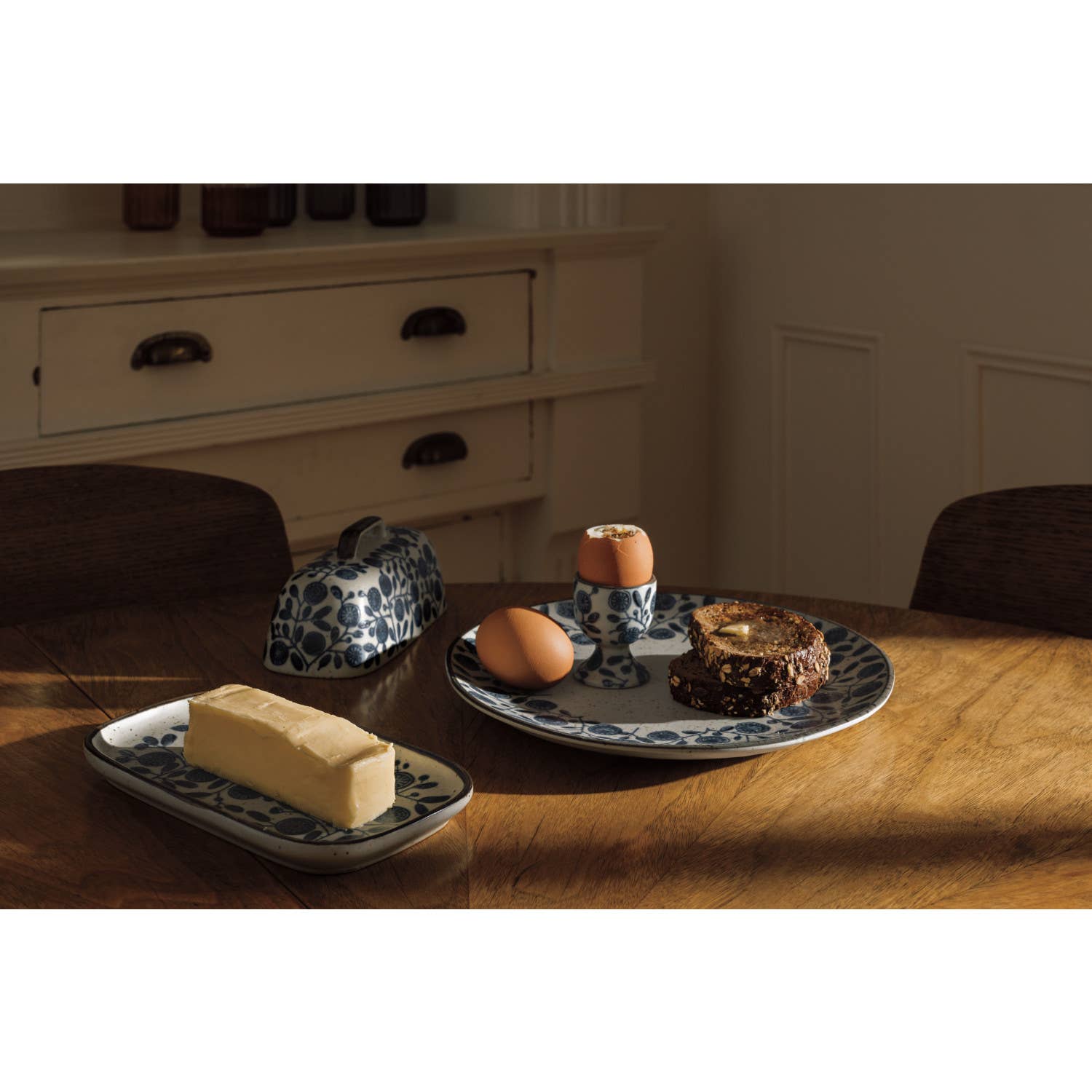 Butter dish, eggs, and a cake on a wooden table with a neutral background