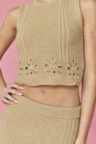 Woman wearing a beige sleeveless crochet top and midi skirt set.