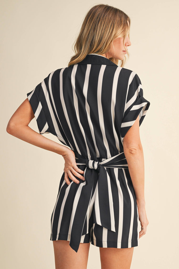 Black and white vertical striped romper with short sleeves, button-up front, and back waist tie