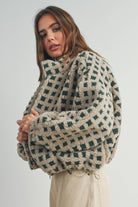 Woman wearing a beige and green checkered fleece jacket with a zip closure, paired with a white crop top and beige corduroy pants.