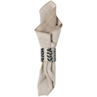 Folded beige napkin with a decorative metal clip on a white background