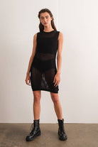 Woman wearing a sleeveless black crochet mini dress.