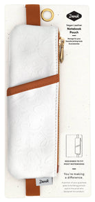 A white vegan leather notebook pouch with an embossed floral design, tan accents, and a gold zipper, attached to its packaging.