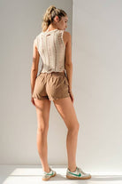 Woman wearing a beige round neck sleeveless ladder knit crop top. 