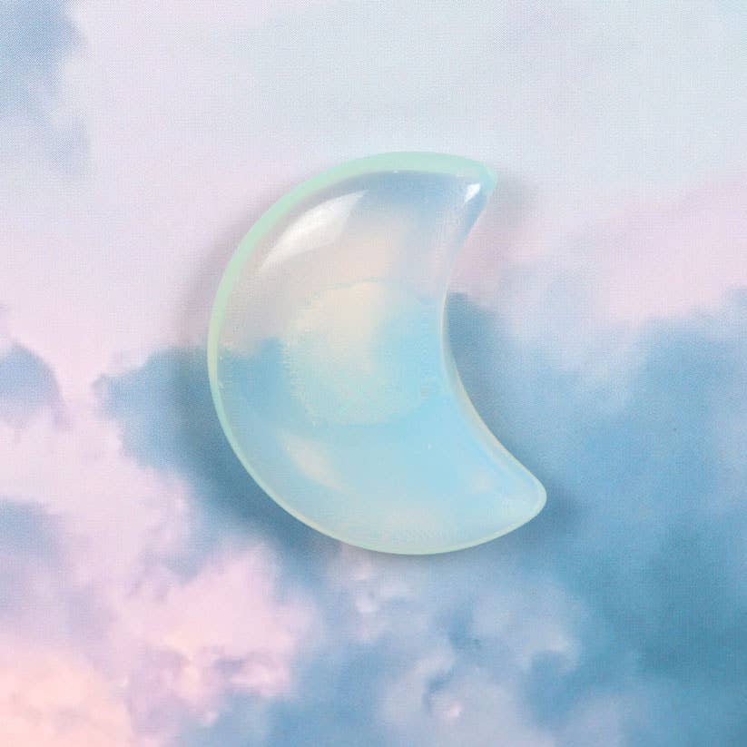 Greeting card with a moonstone crescent moon charm and ‘Stay Wild Moon Child’ text against a dreamy sky background.