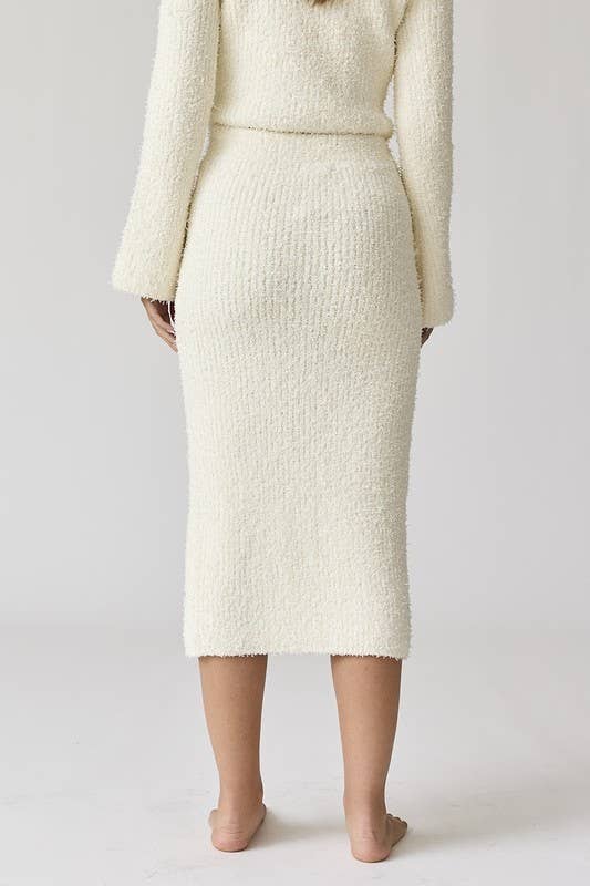 Woman wearing a white round neck long sleeve crop soft knit top and midi skirt set with a side slit.