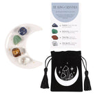 A success crystal set featuring a moon-shaped dish holding four stones (sodalite, aventurine, tiger’s eye, clear quartz), a black pouch with a crystal design, and a healing crystals information card.