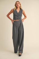 Woman wearing a sleeveless pinstriped vest and matching high-waisted wide-leg trousers.