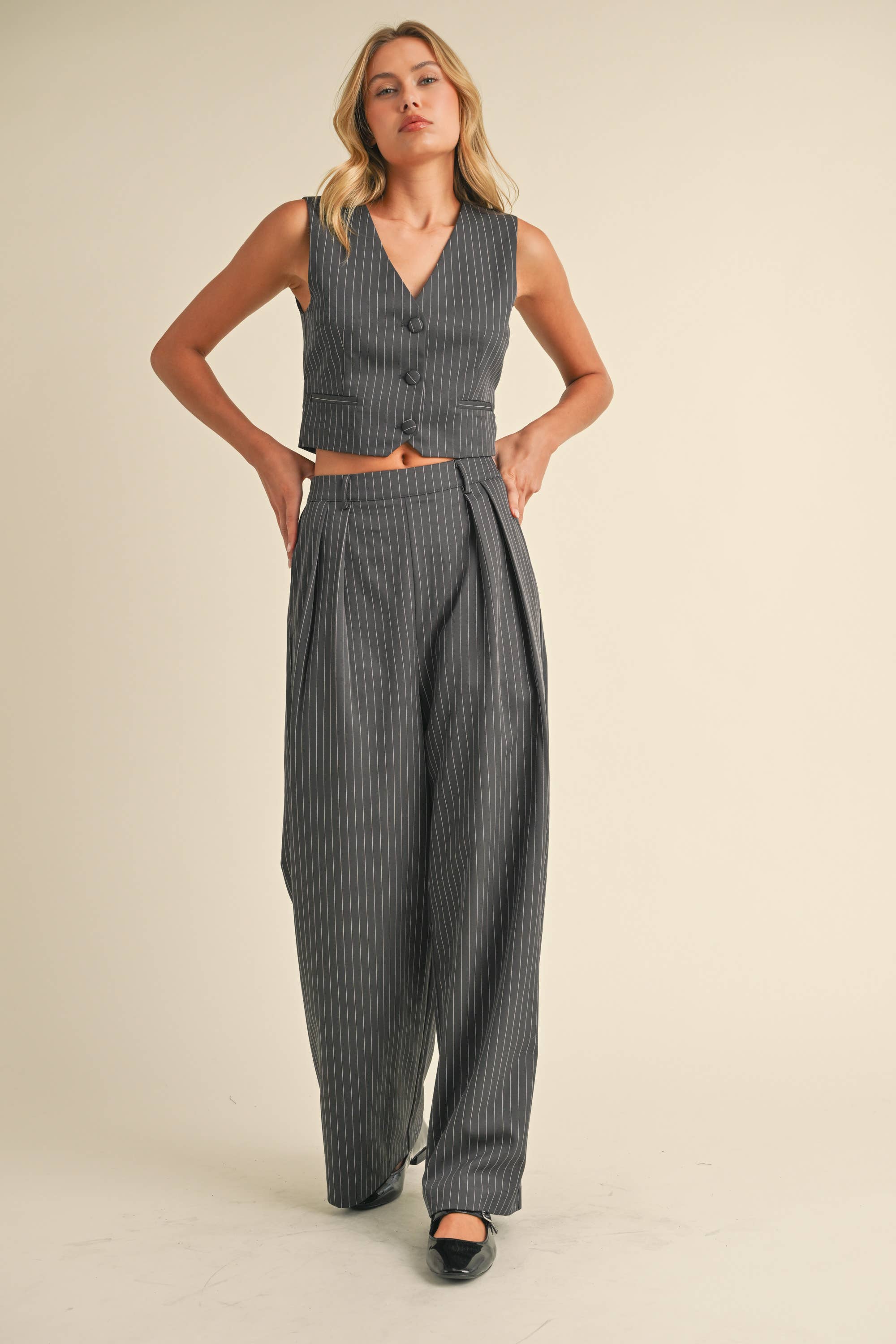 Woman wearing a sleeveless pinstriped vest and matching high-waisted wide-leg trousers.