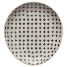 Ceramic spoon rest with a blue and black geometric pattern on a speckled cream background.