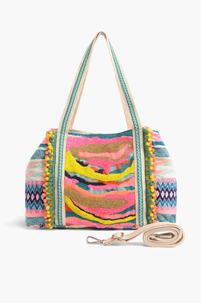 Multicolor embroidered crossbody bag with abstract beading, patterned sides, pom-pom trim, and detachable strap.